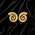 A pair of gold spiral-shaped earrings displayed on a black satin fabric background.
