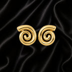 A pair of gold spiral-shaped earrings displayed on a black satin fabric background.